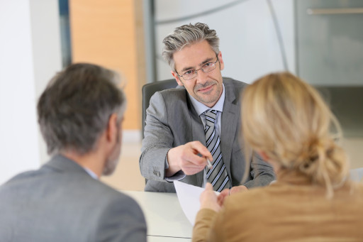 a couple on a meeting with their phycologist, the phycologist looking straight to the woman handing the document and pen mediator for divorce