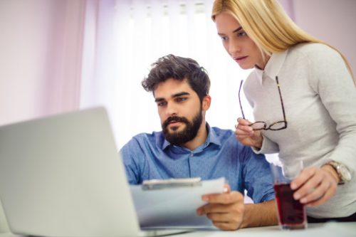 Young businessman and woman working together in office with laptop spousal support