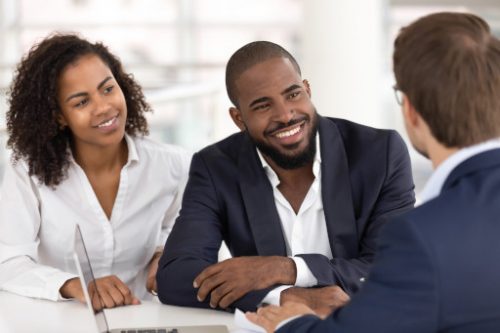 Happy african american young family couple listen to realtor insurer salesman consulting black clients at meeting uncontested divorce