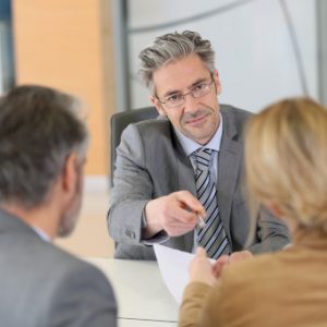 a couple on a meeting with their phycologist, the phycologist looking straight to the woman handing the document and pen mediator for divorce