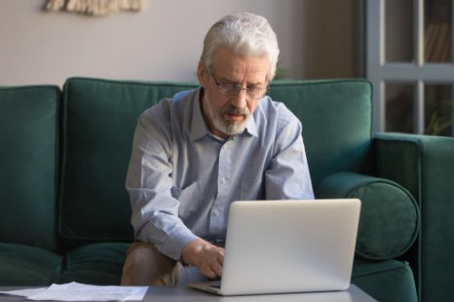 a man sitting on a couch typing on his laptop on the coffee table mediation divorce